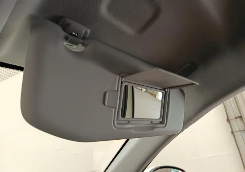Vue intérieure du pare-soleil côté conducteur gris avec miroir de courtoisie ouvert dans une Peugeot 208 blanche.