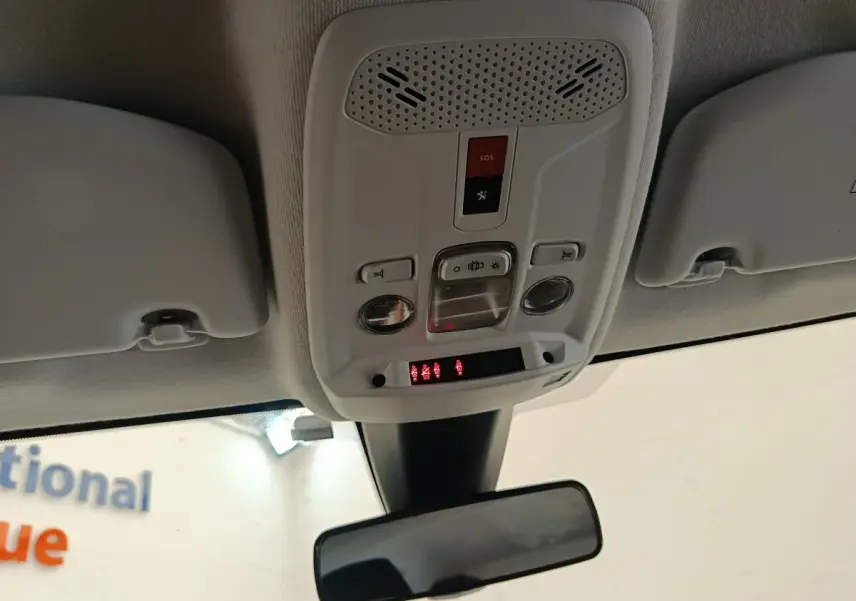 Vue intérieure en plongée du plafonnier blanc avec commandes d’éclairage et bouton SOS dans une Peugeot 208 blanche.