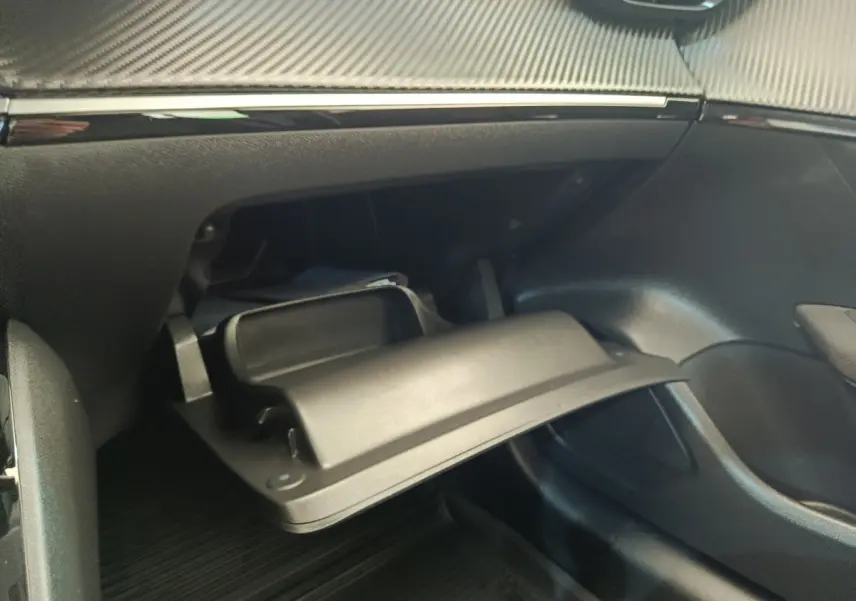 Gant de rangement ouvert côté passager dans l'habitacle noir d'une Peugeot 208 blanche, version PureTech 75 S&S Active Business.