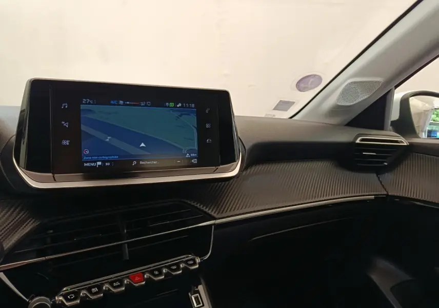 Vue intérieure du tableau de bord de la Peugeot 208 PureTech 75 blanc, avec écran tactile de navigation central.