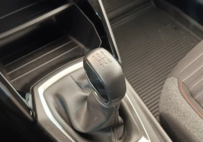 Gros plan sur le levier de vitesses manuel noir de la Peugeot 208 PureTech 75, avec partie tissu et coutures visibles.