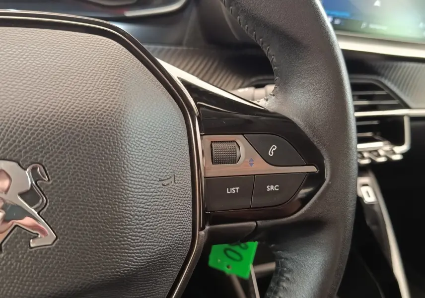 Gros plan sur le volant cuir multifonctions côté droit de la Peugeot 208 blanche, avec commandes audio et téléphone.