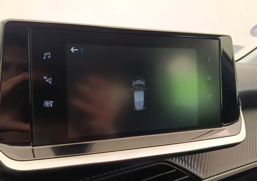 Écran tactile central affichant la vue de dessus du véhicule dans l’habitacle d’une Peugeot 208 blanche.