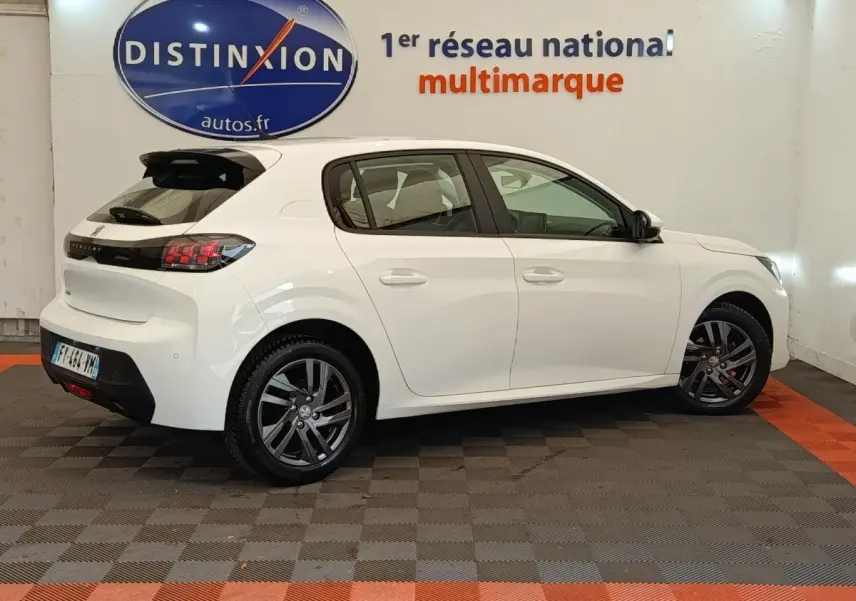 Peugeot 208 blanc vue de côté droit en intérieur, avec jantes alliage et feux arrière LED distinctifs.