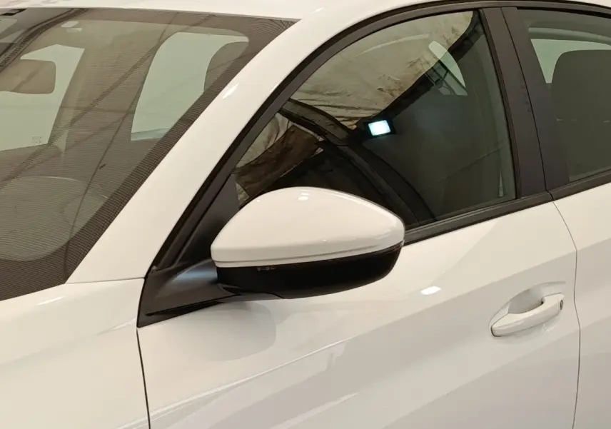 Vue rapprochée du rétroviseur droit blanc et de la portière avant droite d'une Peugeot 208 blanche.