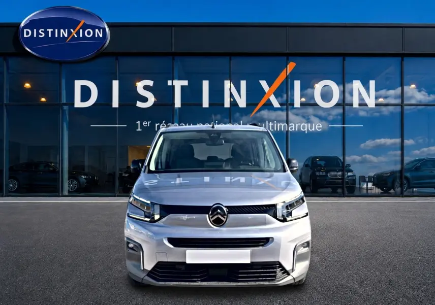 Vue de face d'un Citroën Berlingo 2026 gris acier, avec calandre moderne et phares LED devant un showroom Distinxion.