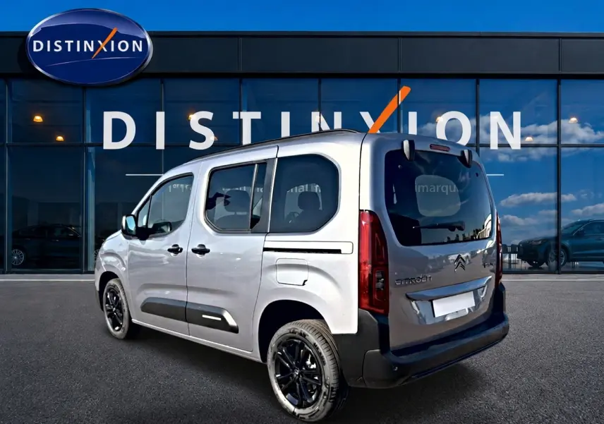 Vue 3/4 arrière droite du Citroën Berlingo gris acier avec jantes noires devant un showroom Distinxion.