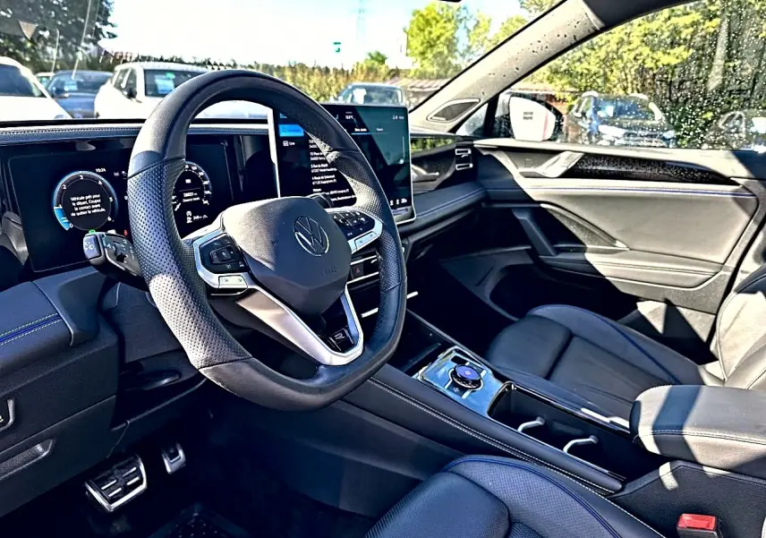 Vue intérieure côté conducteur du Volkswagen Tiguan 2024, volant cuir noir et tableau de bord digital.