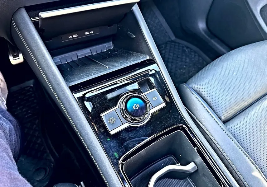 Vue rapprochée de la console centrale noire brillante du Volkswagen Tiguan 2024 avec accoudoir et siège en cuir gris.
