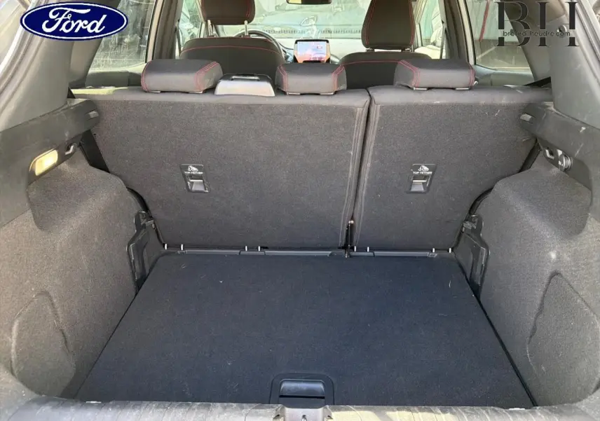 Coffre ouvert de Ford Puma 2024 gris Solar Métallisé, vue arrière montrant banquette arrière avec surpiqûres rouges.
