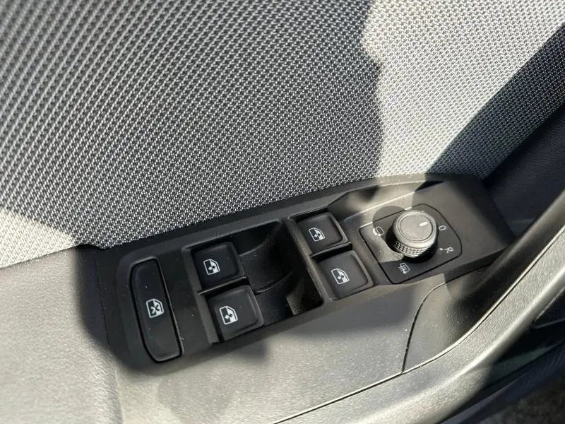 Gros plan sur les commandes des vitres et des rétroviseurs côté conducteur du SEAT LEON ST gris métallisé 2025.