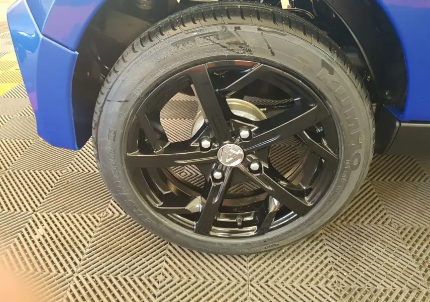 Gros plan sur la roue avant droite noire brillante de l'AIXAM AMBITION 0.5 CITY SPORT bleu 2026.