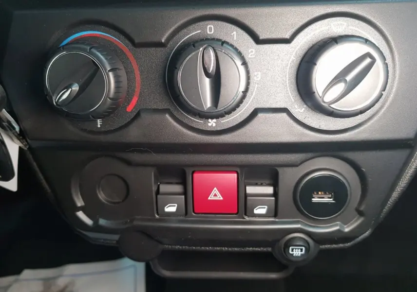Gros plan sur la console centrale de l'AIXAM AMBITION 0.5 CITY SPORT 2026 avec commandes de climatisation et bouton d'alerte rouge.