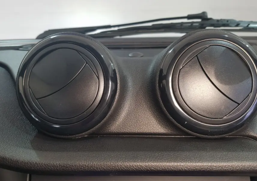 Détail intérieur montrant les deux aérateurs ronds noirs du tableau de bord de l'AIXAM AMBITION 0.5 CITY SPORT bleu 2026.