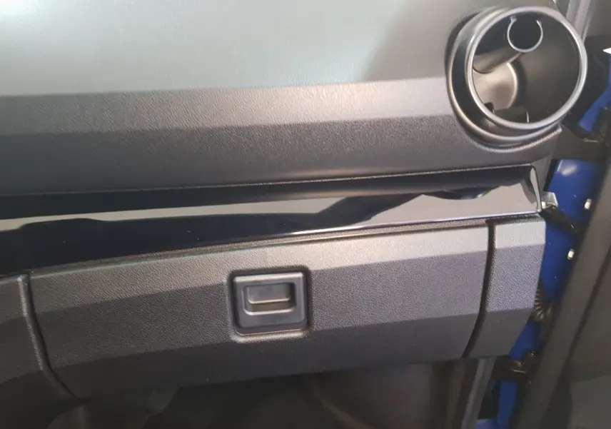 Vue rapprochée de la boîte à gants et de la sortie d'air ronde côté passager d'une Aixam Ambition 0.5 City Sport bleue.