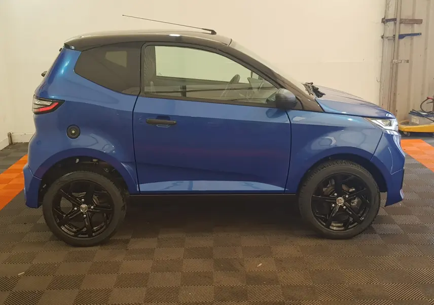 Vue de profil côté gauche d'une Aixam Ambition 0.5 City Sport bleu avec toit noir et jantes noires.