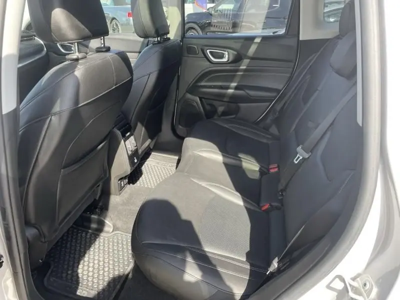 Vue intérieure arrière côté droit du Jeep Compass 2023 gris métal, montrant les sièges arrière en cuir noir et la portière ouverte.