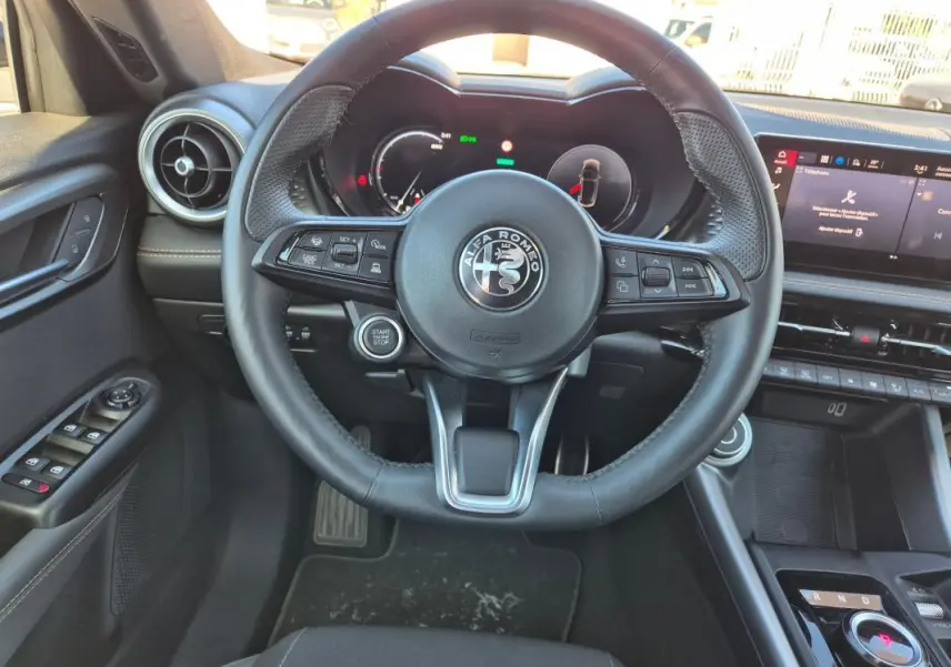 Vue intérieure centrée sur le volant sport de l'Alfa Romeo Tonale 2025, avec tableau de bord numérique et commandes au volant.