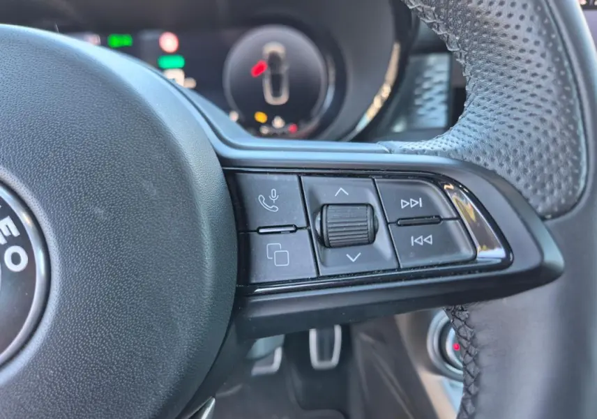 Gros plan sur les commandes multifonctions à droite du volant sport de l'Alfa Romeo Tonale bleu 2025.