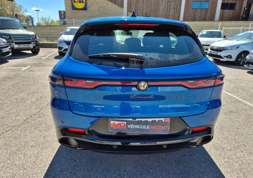 Vue arrière d'une Alfa Romeo Tonale bleu 2025 avec feux arrière LED et double sortie d'échappement noire.