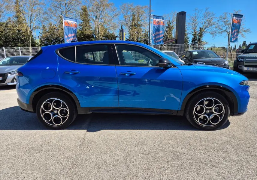 Vue de profil côté gauche d'un Alfa Romeo Tonale bleu 2025 avec jantes alliage distinctives et rétroviseurs noirs.