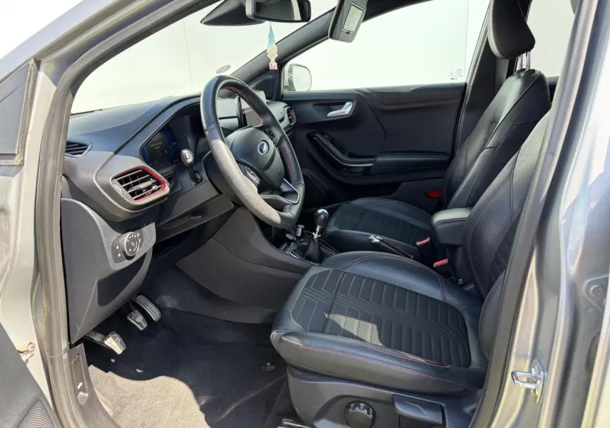 Vue intérieure côté conducteur du Ford Puma gris métal 2020, sièges noirs avec surpiqûres rouges et volant ST-Line.