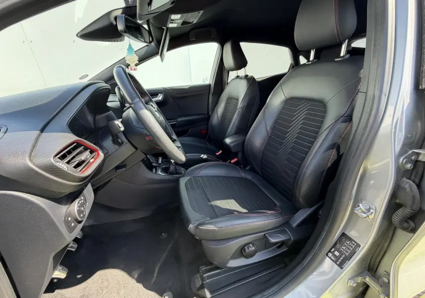 Vue intérieure côté conducteur du Ford Puma gris métal 2020, sièges noirs avec surpiqûres rouges et volant ST-Line.