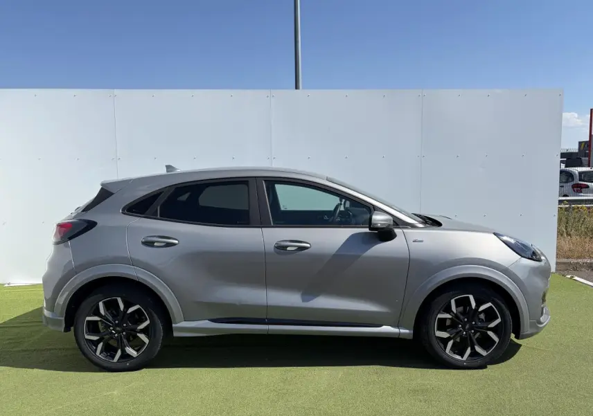 Vue latérale droite d'un Ford Puma gris métal avec jantes alliage noires et badges ST-Line visibles.