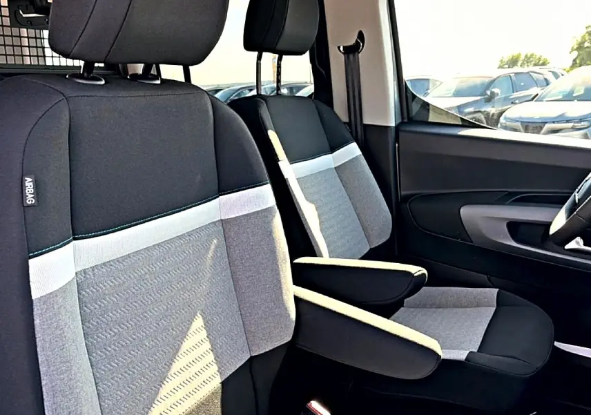 Vue rapprochée des sièges avant gris clair et noir du Citroën Berlingo N1 2026 avec accoudoirs centraux déployés.