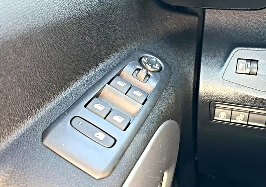 Gros plan sur les commandes de vitres électriques et rétroviseurs côté conducteur du Citroën Berlingo gris acier 2026.