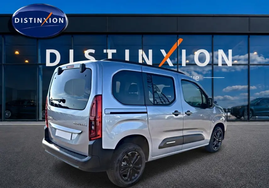 Vue 3/4 arrière droite d'un Citroën Berlingo 2026 gris acier avec barres de toit et jantes alu noires.