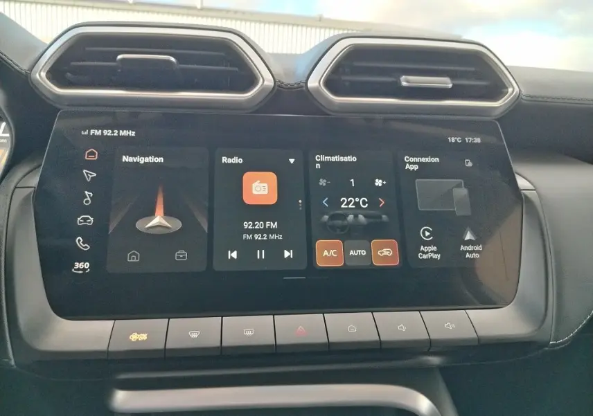 Écran tactile central du MG MOTOR ZS 1.5 l Hybrid 2026, affichant navigation, radio et climatisation, intérieur noir.