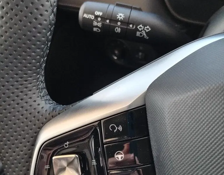 Détail du volant côté gauche du MG MOTOR ZS 1.5 l Hybrid 2026 en Cosmic Silver, avec commandes intégrées et commandes de phares.