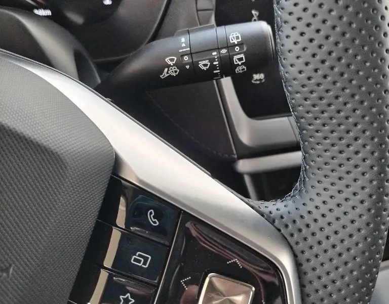 Gros plan sur la commande de volant en cuir perforé noir et la manette d’essuie-glace du MG MOTOR ZS 1.5 l Hybrid + 197 Luxury Cosmic Silver.