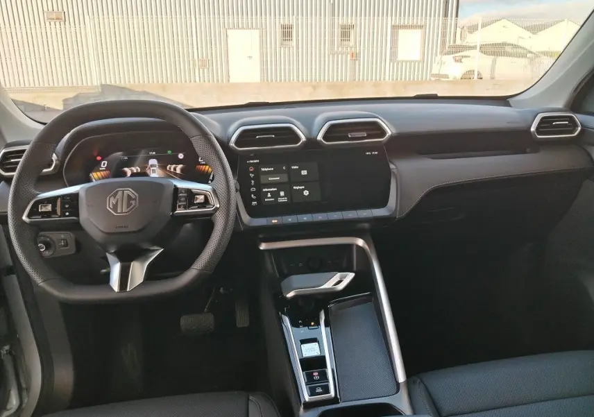 Vue intérieure frontale du tableau de bord et volant noir du MG ZS 1.5 l Hybrid + 197 Luxury, avec écran tactile central.