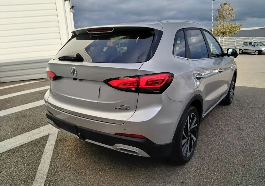 Vue 3/4 arrière droite du MG ZS 1.5 l Hybrid Cosmic Silver, avec feux arrière LED et jantes alliage distinctives.