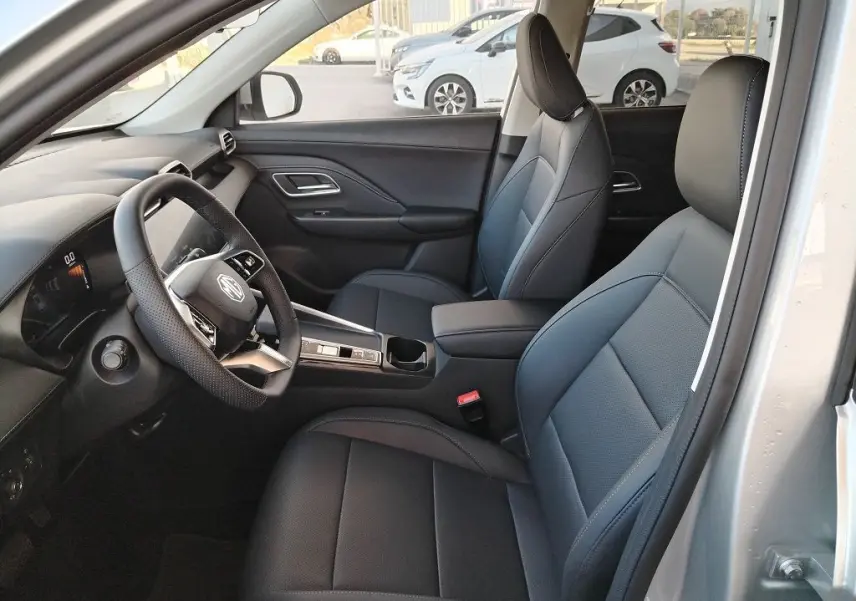 Vue intérieure côté conducteur du MG MOTOR ZS 1.5 l Hybrid 2026 en Cosmic Silver, sièges cuir noir et tableau de bord moderne.