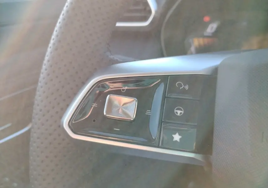 Gros plan sur les commandes du volant côté gauche du MG MOTOR ZS 1.5 l Hybrid + 197 LUXURY en intérieur noir.