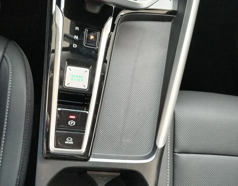 Vue plongeante sur la console centrale noire du MG MOTOR ZS 1.5 l Hybrid 197 LUXURY avec levier de vitesses et bouton start/stop.