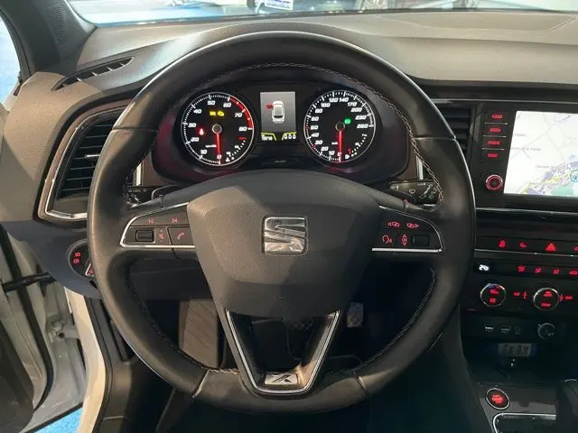 Vue rapprochée du volant et du tableau de bord noir du SEAT Ateca blanc Nevada avec affichage digital et commandes au volant.