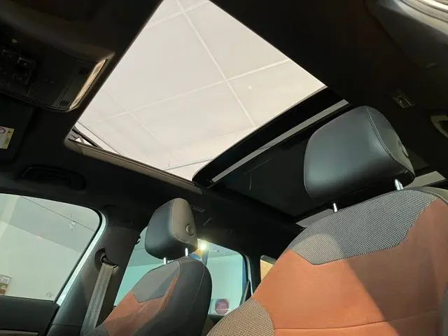 Intérieur du SEAT Ateca 2017 avec sièges bi-matière noir et brun, vue sur toit ouvrant panoramique ouvert.