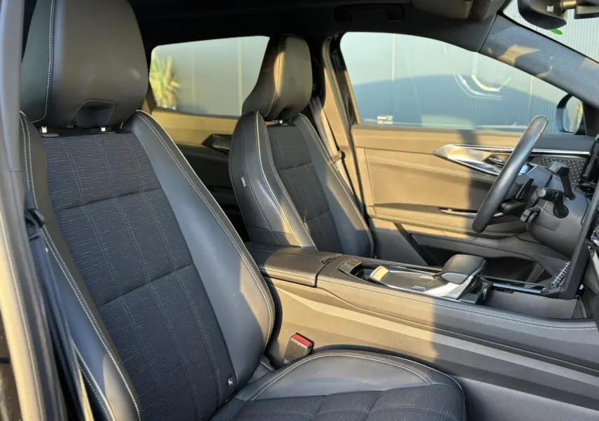 Vue intérieure côté droit du Renault Austral 2023 avec sièges mixtes similicuir et tissu carbone foncé aux surpiqûres or.