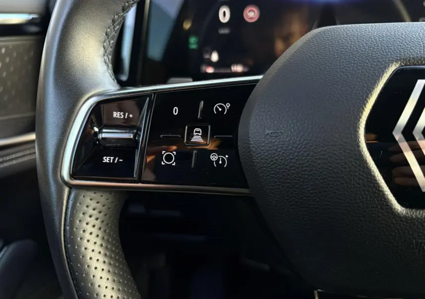 Gros plan sur la partie gauche du volant cuir perforé du Renault Austral 2023 avec commandes de régulateur adaptatif.