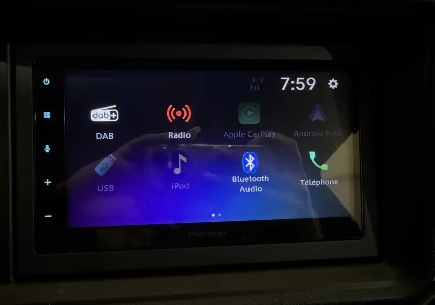 Écran tactile multimédia allumé dans l'habitacle de l'AIXAM AMBITION 0.5 CROSSOVER PREMIUM gris foncé, vue frontale.
