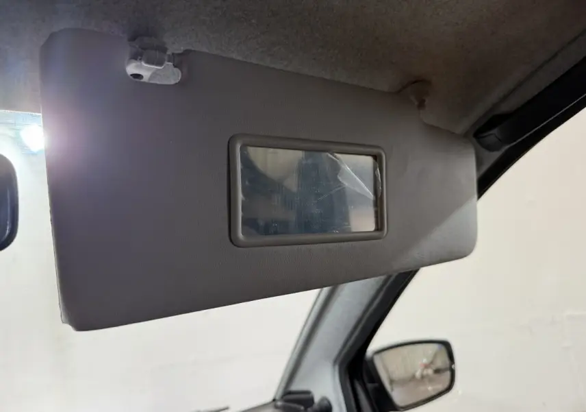 Détail du pare-soleil côté conducteur avec miroir intégré dans l’habitacle d’une Aixam Ambition gris foncé.