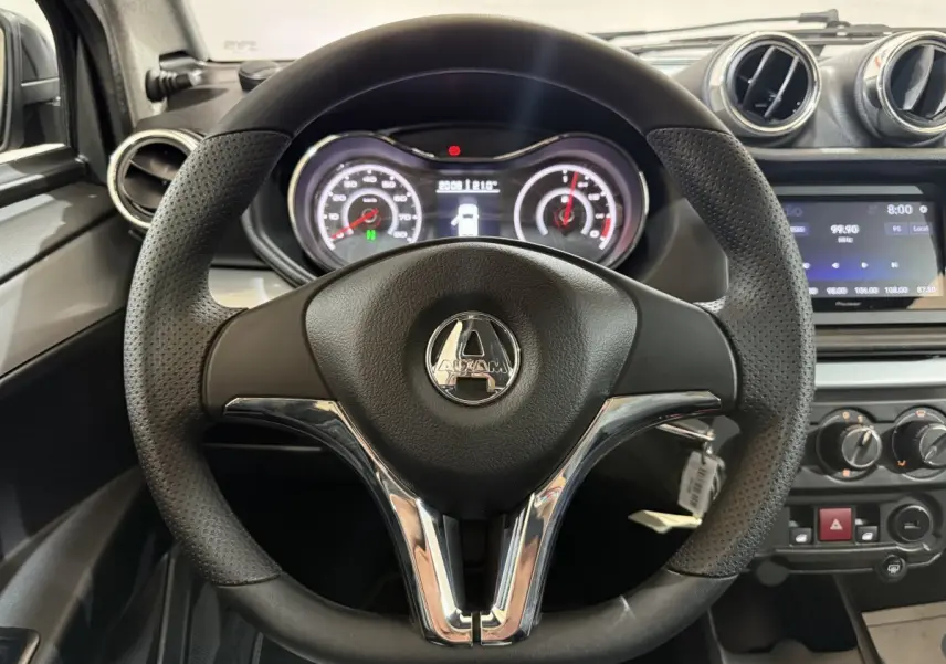 Vue rapprochée du volant noir et perforé de l'AIXAM AMBITION 0.5 CROSSOVER PREMIUM gris foncé, avec tableau de bord et écran central.