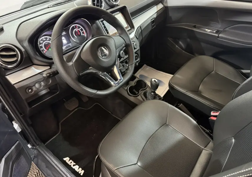 Vue intérieure de l'AIXAM AMBITION 0.5 CROSSOVER PREMIUM 2026, montrant le tableau de bord et les sièges en cuir noir.