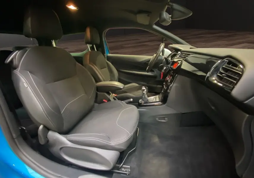 Vue intérieure côté conducteur de la Citroën DS3 bleu avec sièges tissu noir et tableau de bord moderne.