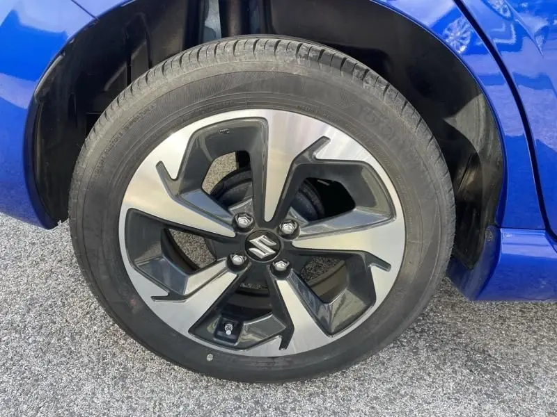 Gros plan sur la roue avant droite d’une Suzuki Swift 2024 bleu métal, avec jante alliage au design moderne bicolore.