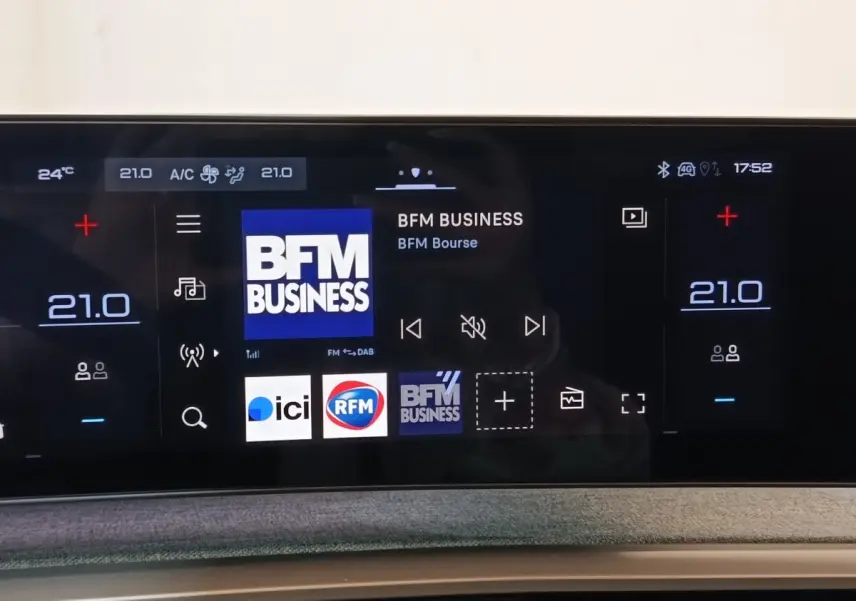 Écran tactile central du tableau de bord du Peugeot 5008 gris clair, affichant la radio BFM Business.